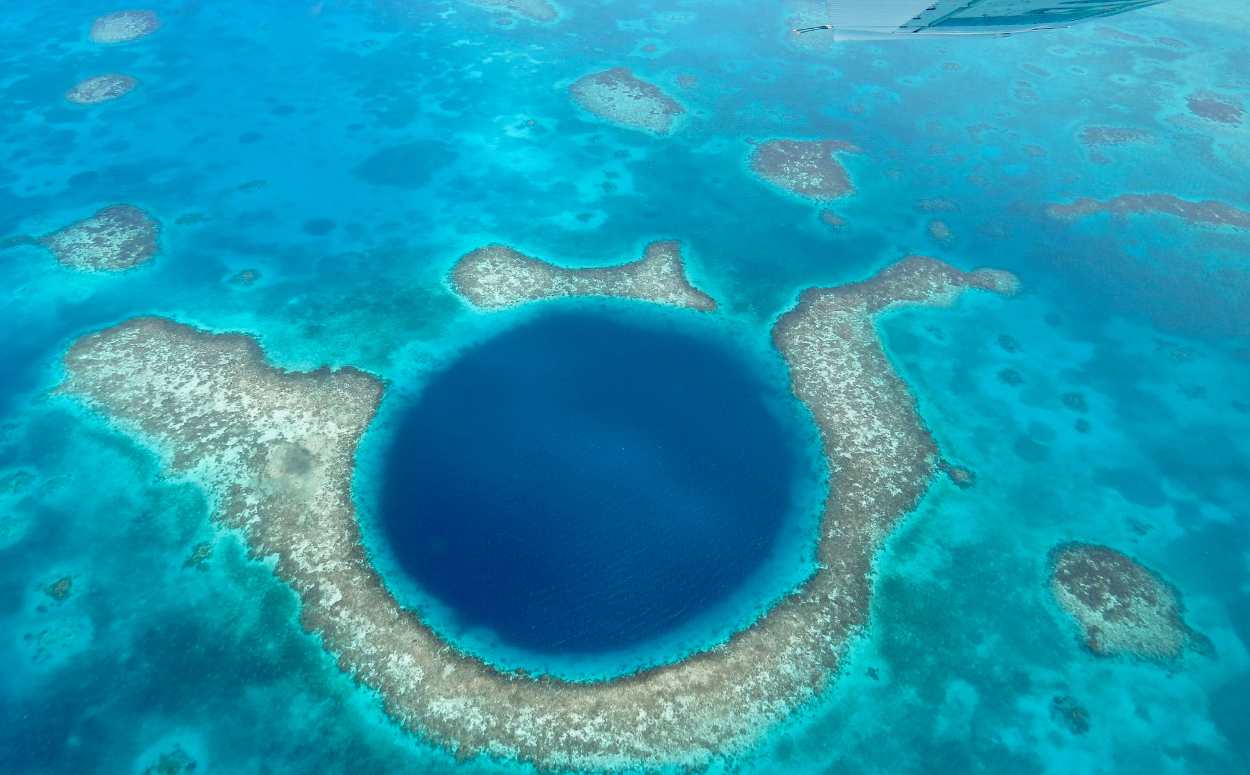 Aerial view of the Great Blue Hole, a massive marine sinkhole and iconic sea creature diving site off the coast of Belize